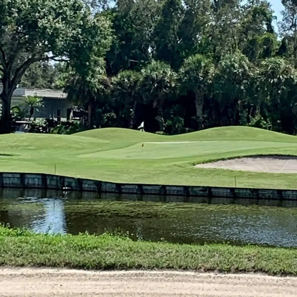 A golf course with water and trees in the background.