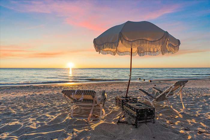 A beach with chairs and an umbrella on it