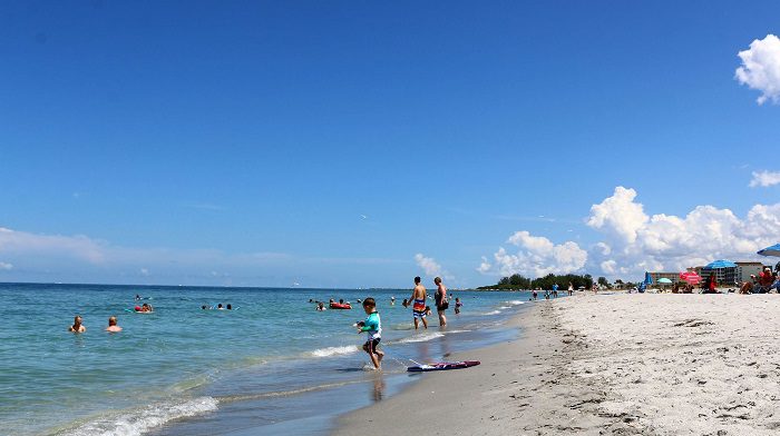 A group of people on the beach near water.